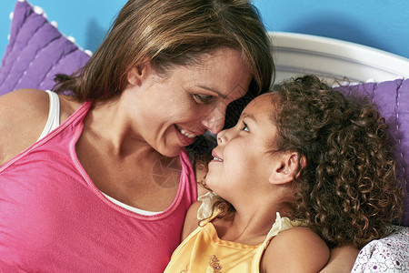 母亲和女儿在床上贴鼻子微笑图片
