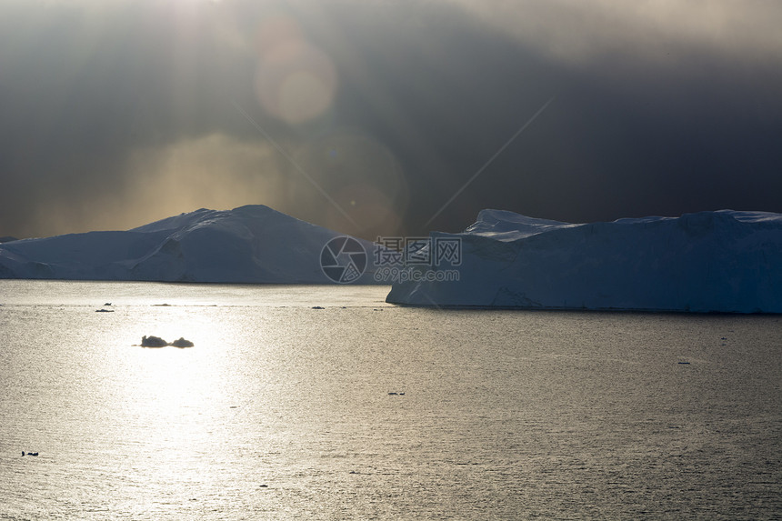 格陵兰迪斯科湾冰山的上空暴风云和阳光图片
