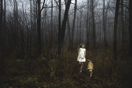 身着白裙子的女孩在森林中溜狗同伴高清图片素材