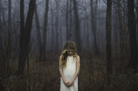 在迷雾的森林中低头的女孩一人高清图片素材