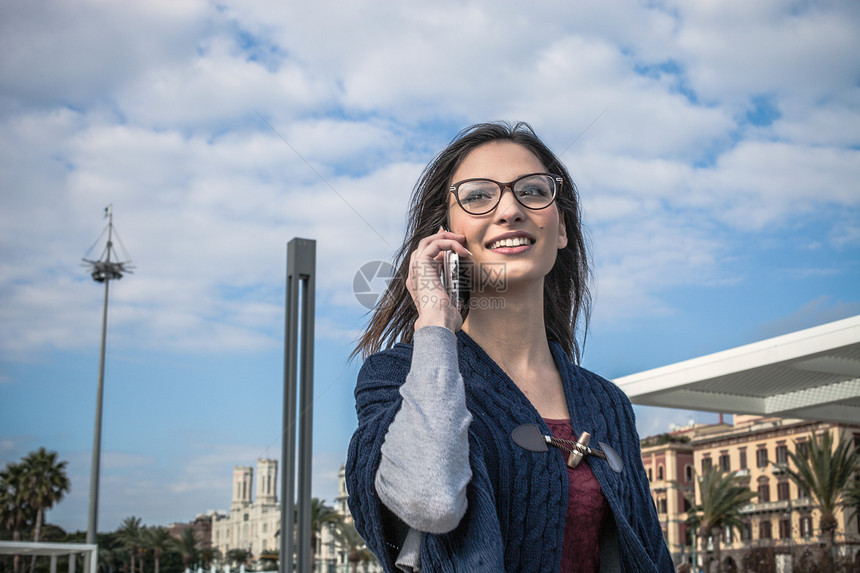 戴眼镜的年轻女子使用智能手机微笑的低角度视图图片