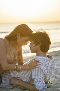 西班牙马略卡岛日落时躺在海滩上的一对浪漫的年轻夫妇图片