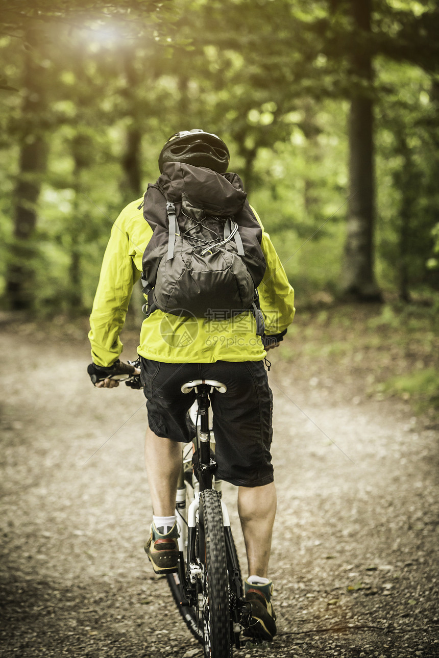 在森林中骑自行车的成年男山上骑自行车者的近视图片