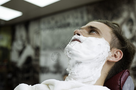 在理发店的年轻男青脸被剃须霜蒙上朝看图片