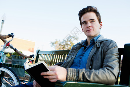 年轻人在公园长椅上读书图片