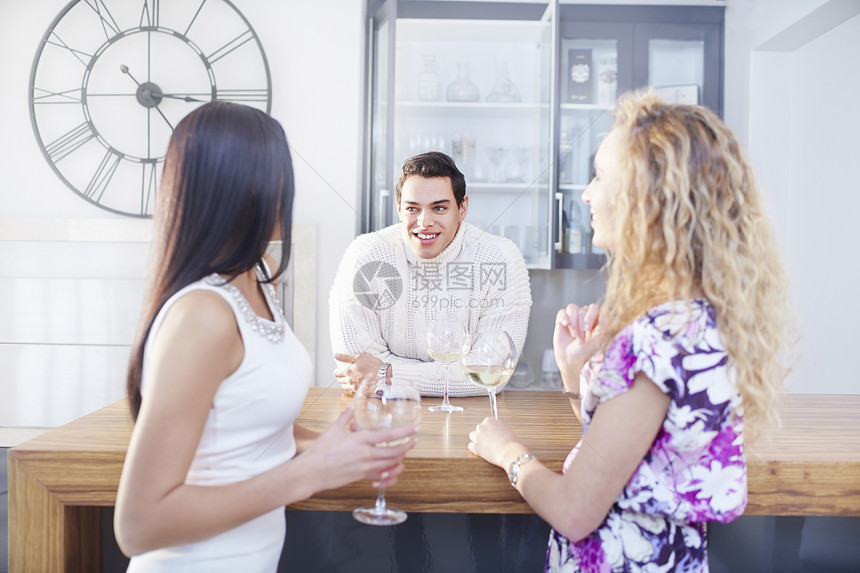三个年轻的成朋友在厨房聊天和喝酒图片