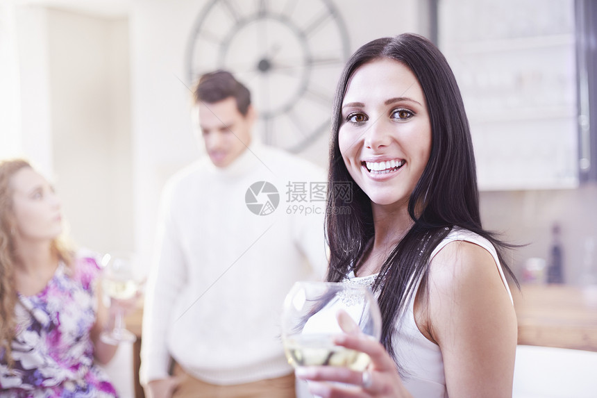 年轻妇女在厨房喝酒的肖像图片