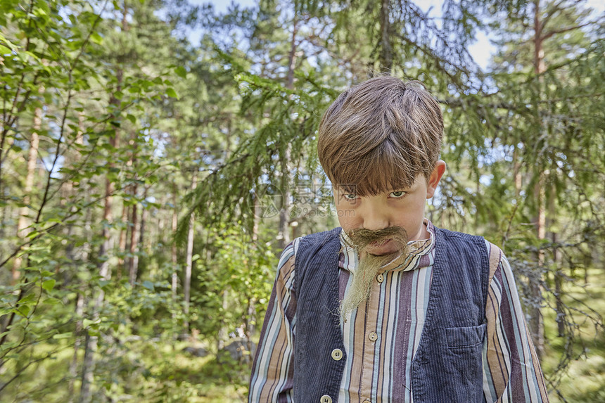 在森林中披胡子和伪装的男孩肖像图片
