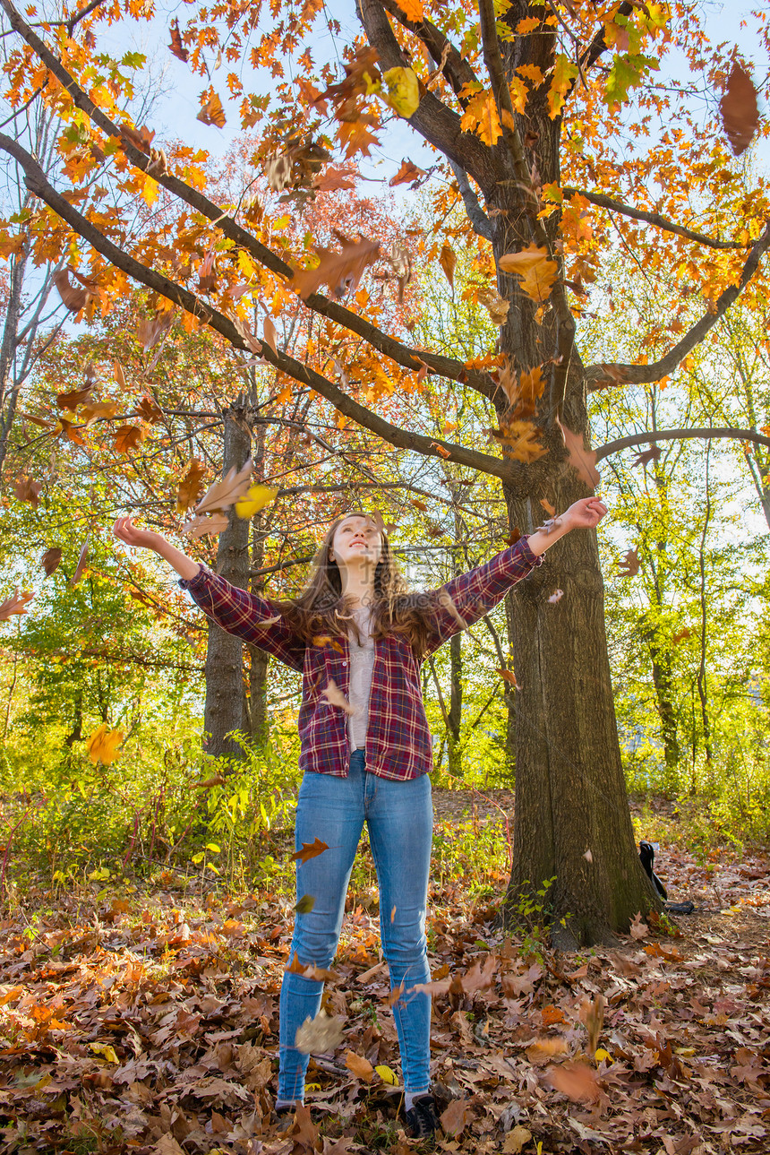 女孩在森林里扔秋叶图片