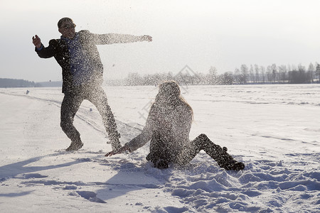 年轻夫妇在雪覆盖的田野玩耍图片