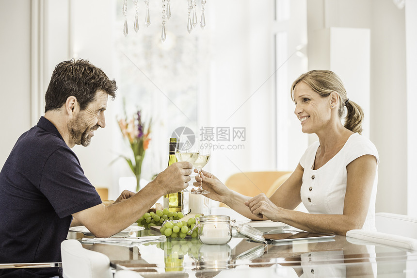 坐在桌边的一对成熟夫妇拿着酒杯庆祝图片