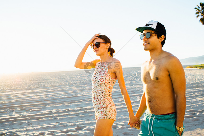 穿着泳装的年轻夫妇在美国加利福尼亚州威斯海滩上漫步图片