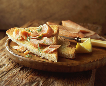 木盘上加番茄和柠檬片的烤鲑鱼图片