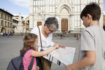 老妇人和孙子孙女在广场上看地图图片