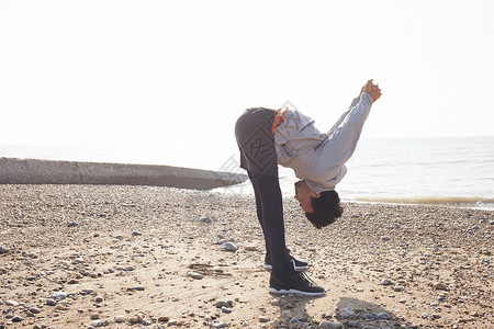 年轻人在布莱顿海滩训练弯腰热身图片