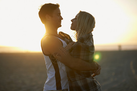 户外海滩日落时拥抱的情侣男性的高清图片素材