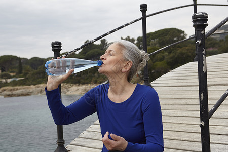 室外用水瓶喝的老妇人图片
