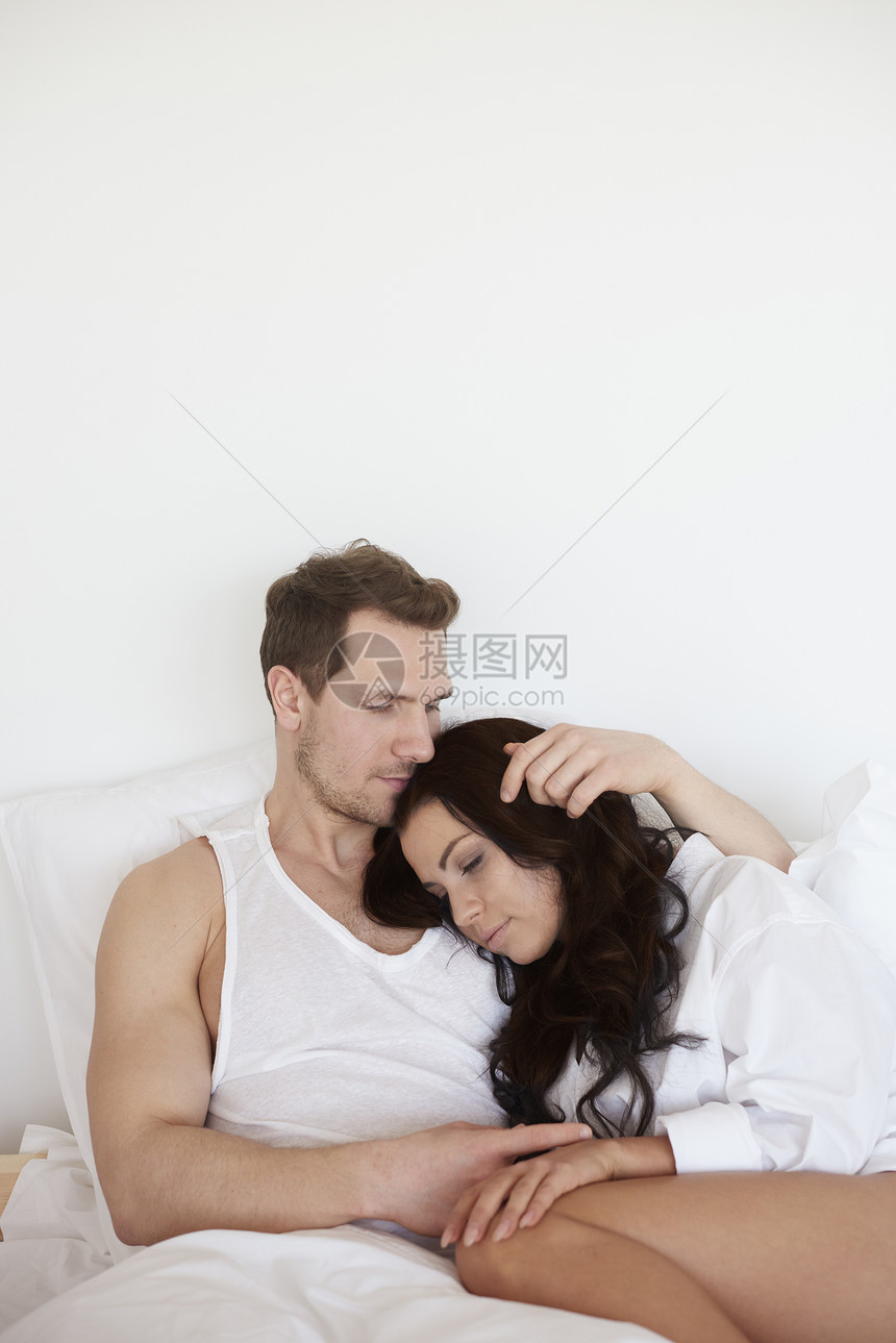 年轻女人睡在床上的男朋友肩上图片