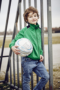 男孩对着扶足球的栏杆看着镜头微笑图片