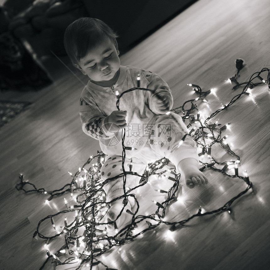 女孩在地板上玩圣诞节灯图片