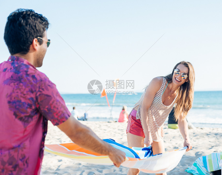 美国加利福尼亚州圣莫卡的海滩上准备睡垫的年轻夫妇图片