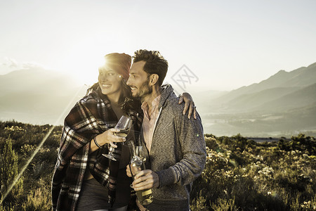 在野外的情侣拿着葡萄酒杯向远看幸福高清图片素材