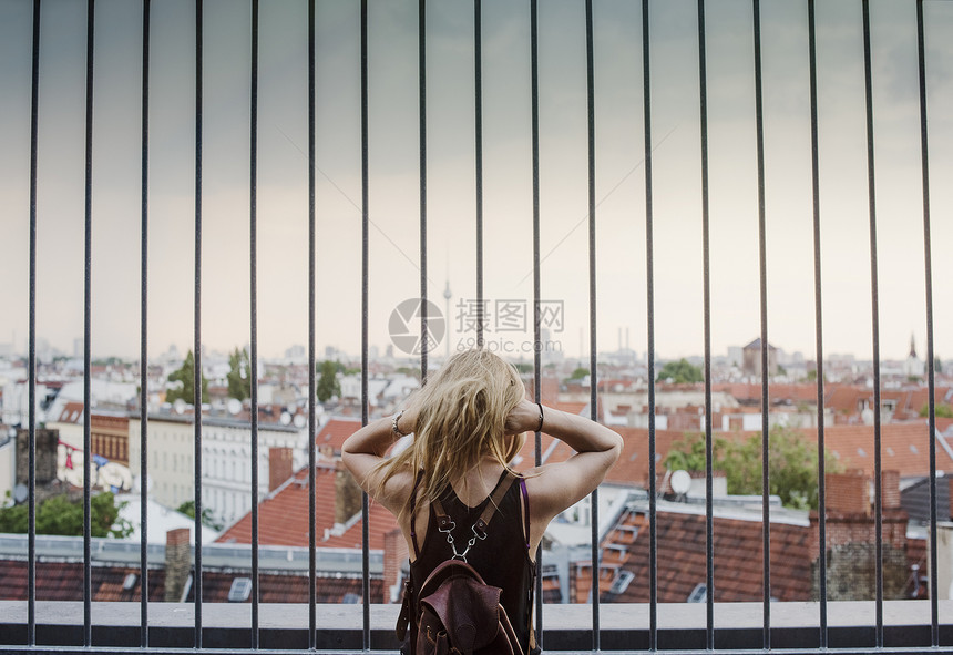 年轻女孩透过栏杆仰望屋顶的风景图片