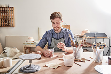 男子在工坊在陶器上绘画图片
