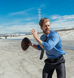 在美国加利福尼亚州洛杉矶河玩美式足球的商务男士图片