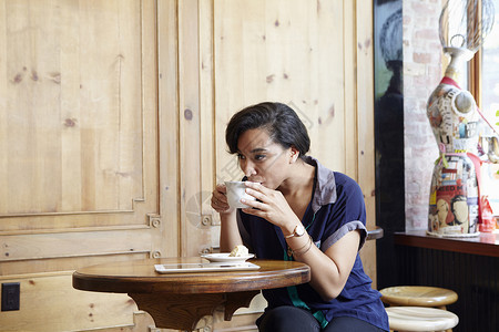 坐在咖啡馆喝咖啡的年轻女子背景图片