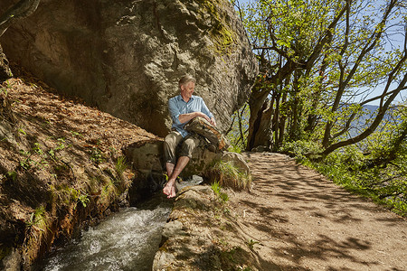 意大利南蒂罗尔梅兰赤脚坐在石头上的男人图片