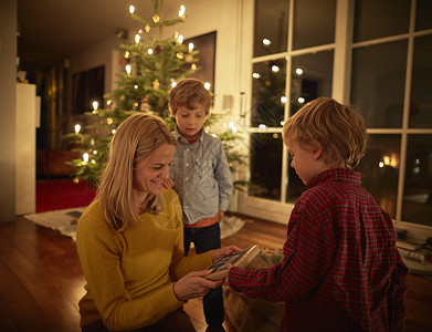 母亲和儿子坐在家中交换圣诞礼物背景图片