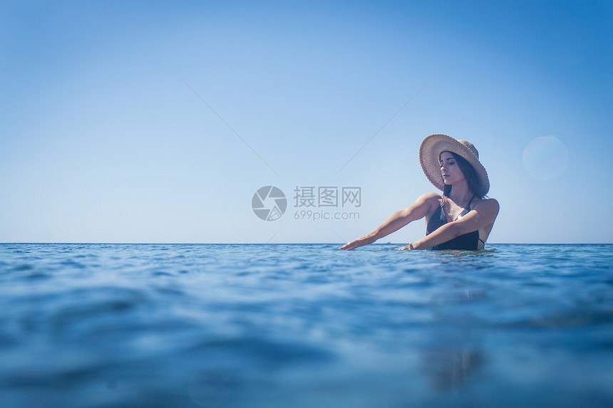 意大利撒丁岛比亚西米乌斯深蓝海穿防晒帽的年轻女子图片