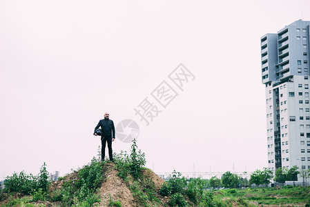 男摩托车手站在荒地山顶上的肖像图片