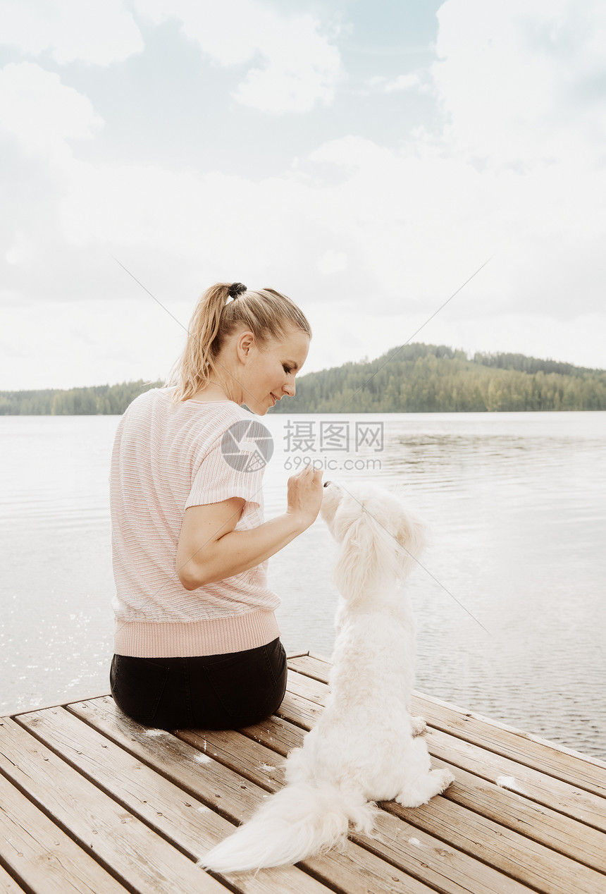 女人和宠物狗在码头边图片