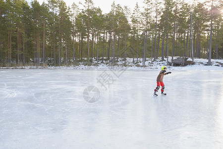 男孩在冰冻湖上滑行背景图片