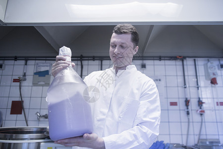 实验室内拿着大瓶化学剂的科学家图片