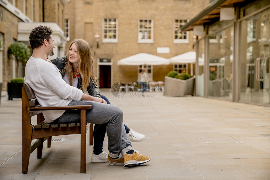坐在英国伦敦KingsRoad国王路长椅聊天的年轻夫妇图片