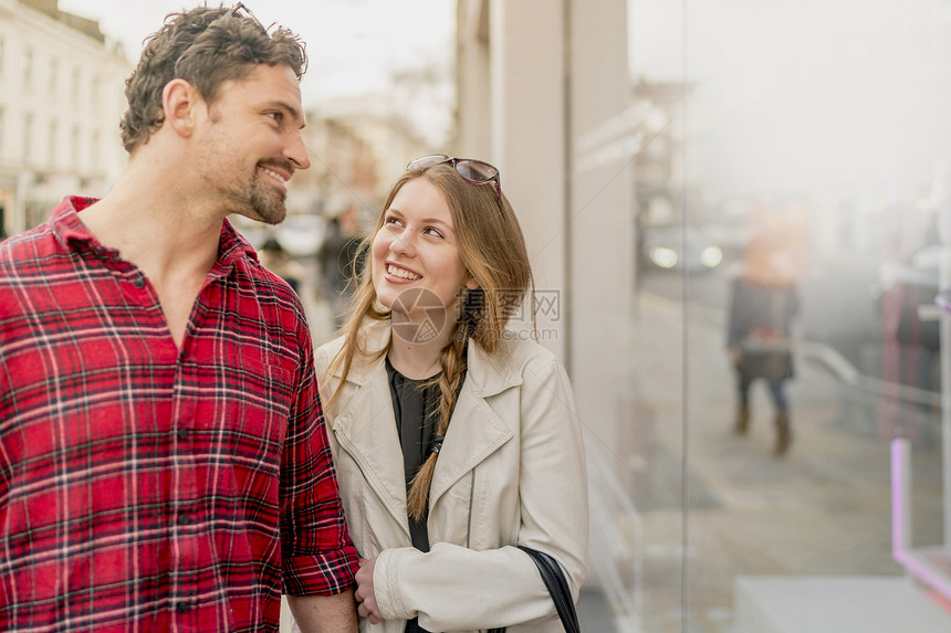 在英国伦敦KingsRoad的年轻夫妇路过商店橱窗图片