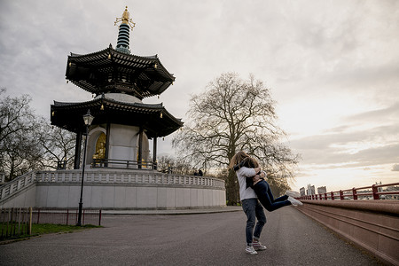 罗马青年男子在英国伦敦Battersea公园抱起女友，拥抱彼此，成年女子高清图片素材