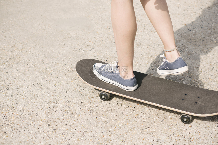 年轻女滑板运动员的腿，帆布鞋，滑板，图片