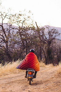 美国加利福尼亚州塞科公园后视角骑摩托车裹着毯子后视线的男人图片