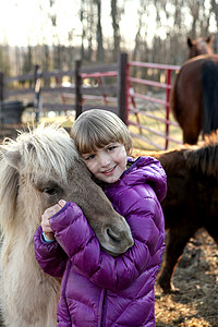 年轻女孩户外的肖像拥抱小马动物主题高清图片素材