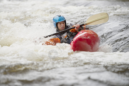 不平衡的男子皮划艇运动员在迪河激流中划水图片