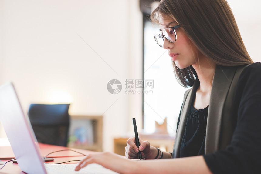 使用笔记本电脑在办公桌的年轻妇女图片