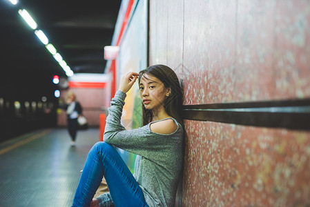 晚上坐在火车站台地板上的年轻妇女图片