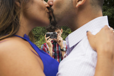 儿子用照相机拍父母亲吻的照片图片