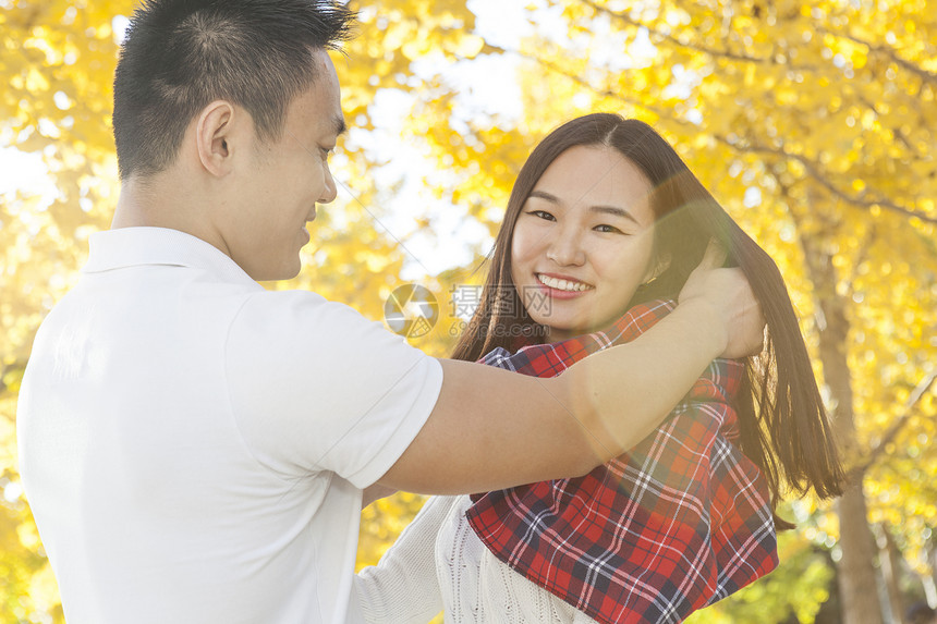 秋天公园里小伙子将围巾围在女友身上图片