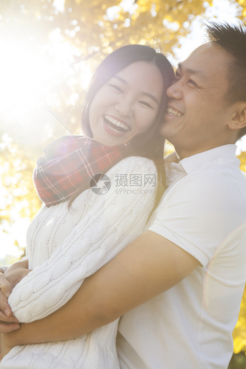 秋天公园里拥抱在一起的的年轻夫妇图片