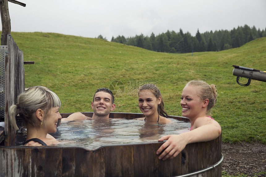 四位成年朋友在奥地利蒂罗尔市萨特尔伯格姆的乡村温泉浴场放松时大笑图片
